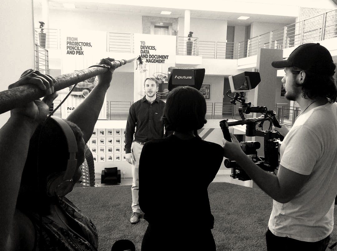 Crew with boom microphone and gimbal filming a presenter in an office atrium