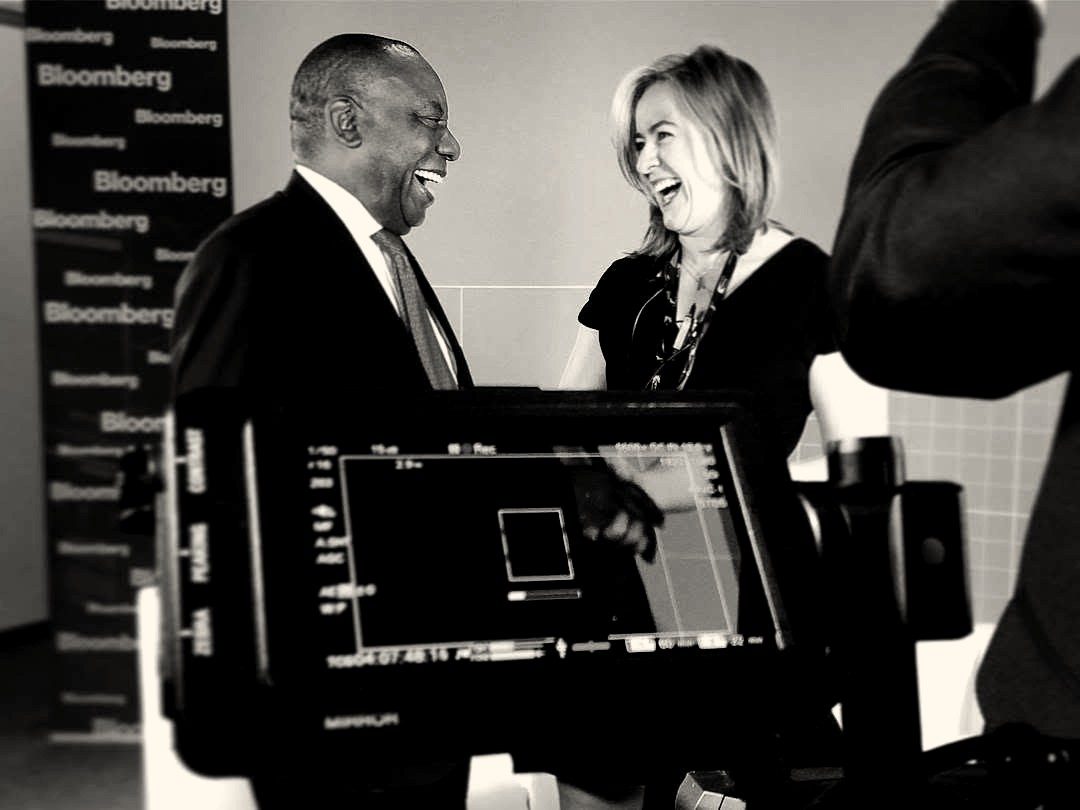 Camera monitor in the foreground as an interviewer and guest share a laugh on a Bloomberg set