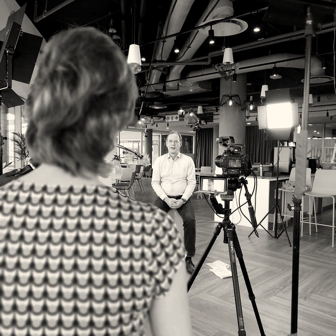 A seated executive being interviewed in a modern office under studio lighting