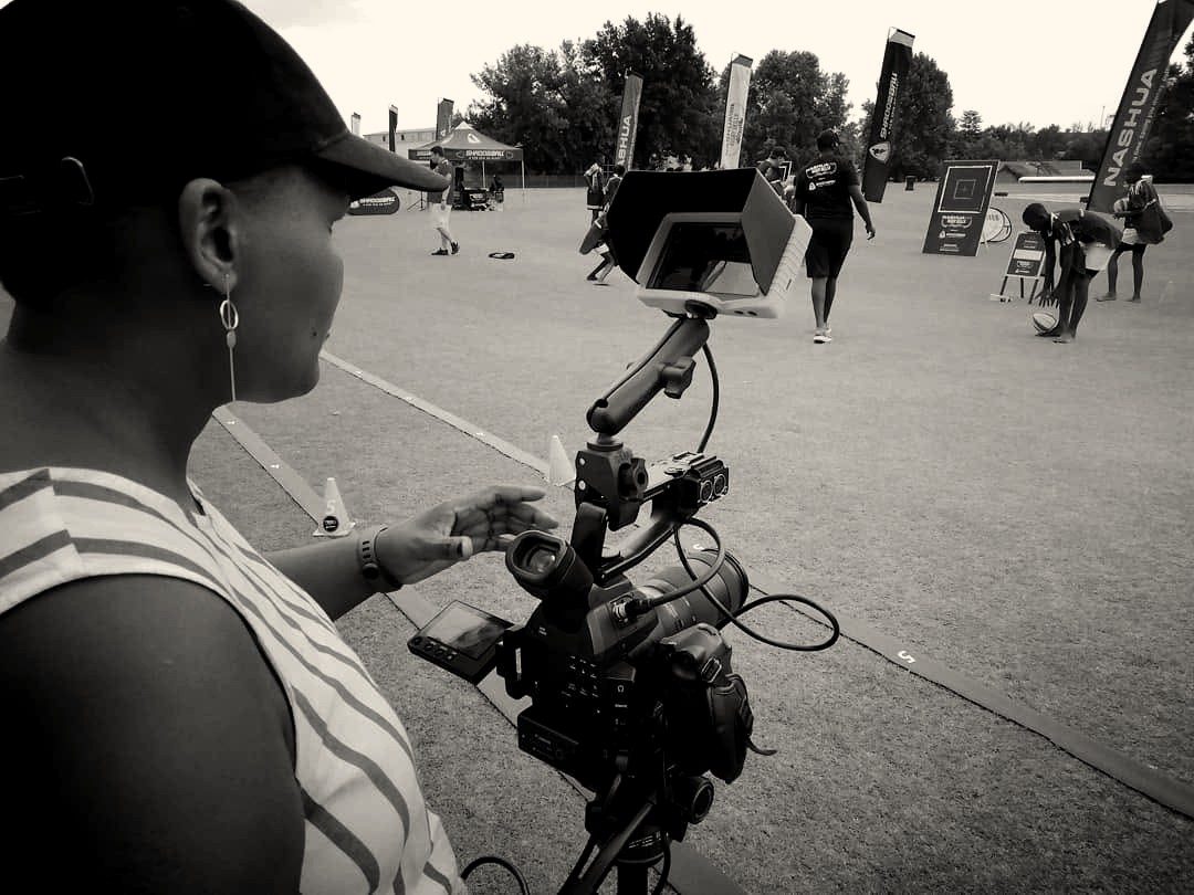 A camera operator framing a shot on a sports field