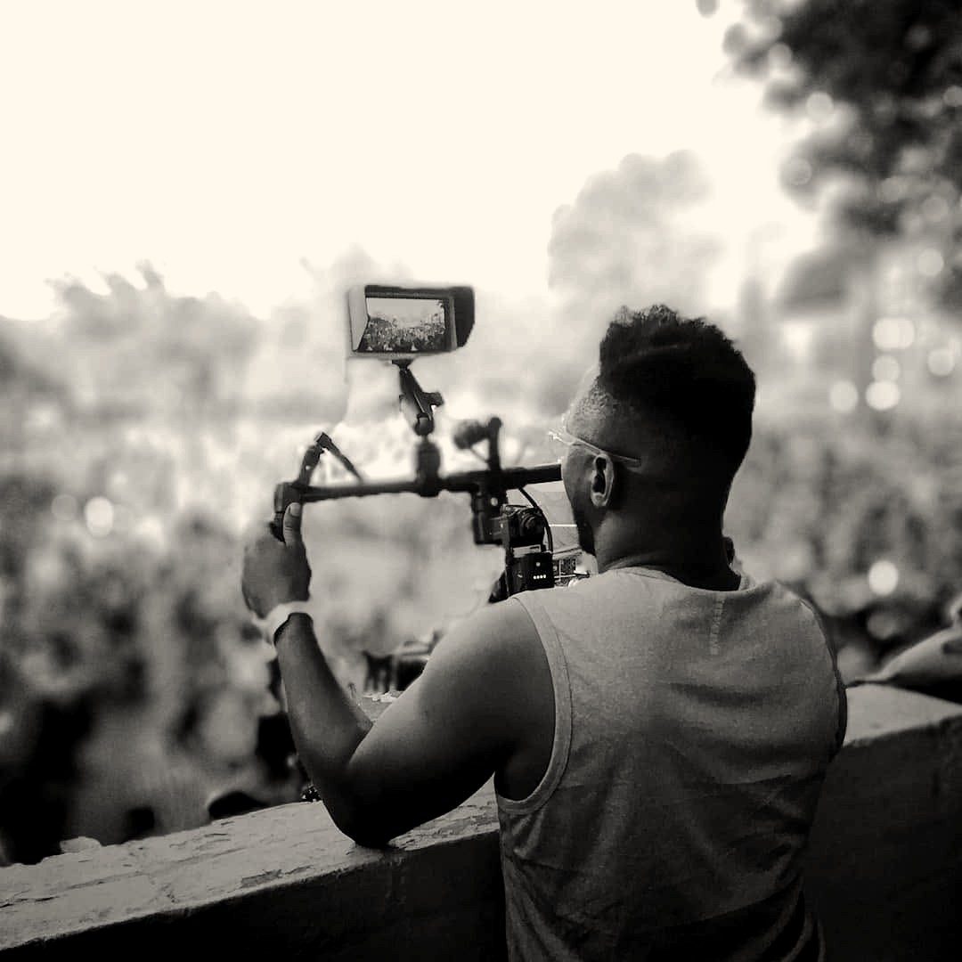 A camera operator filming a large crowd from a balcony with a gimbal rig