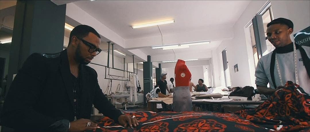 Film still: a designer examining patterned fabric in a clothing workshop